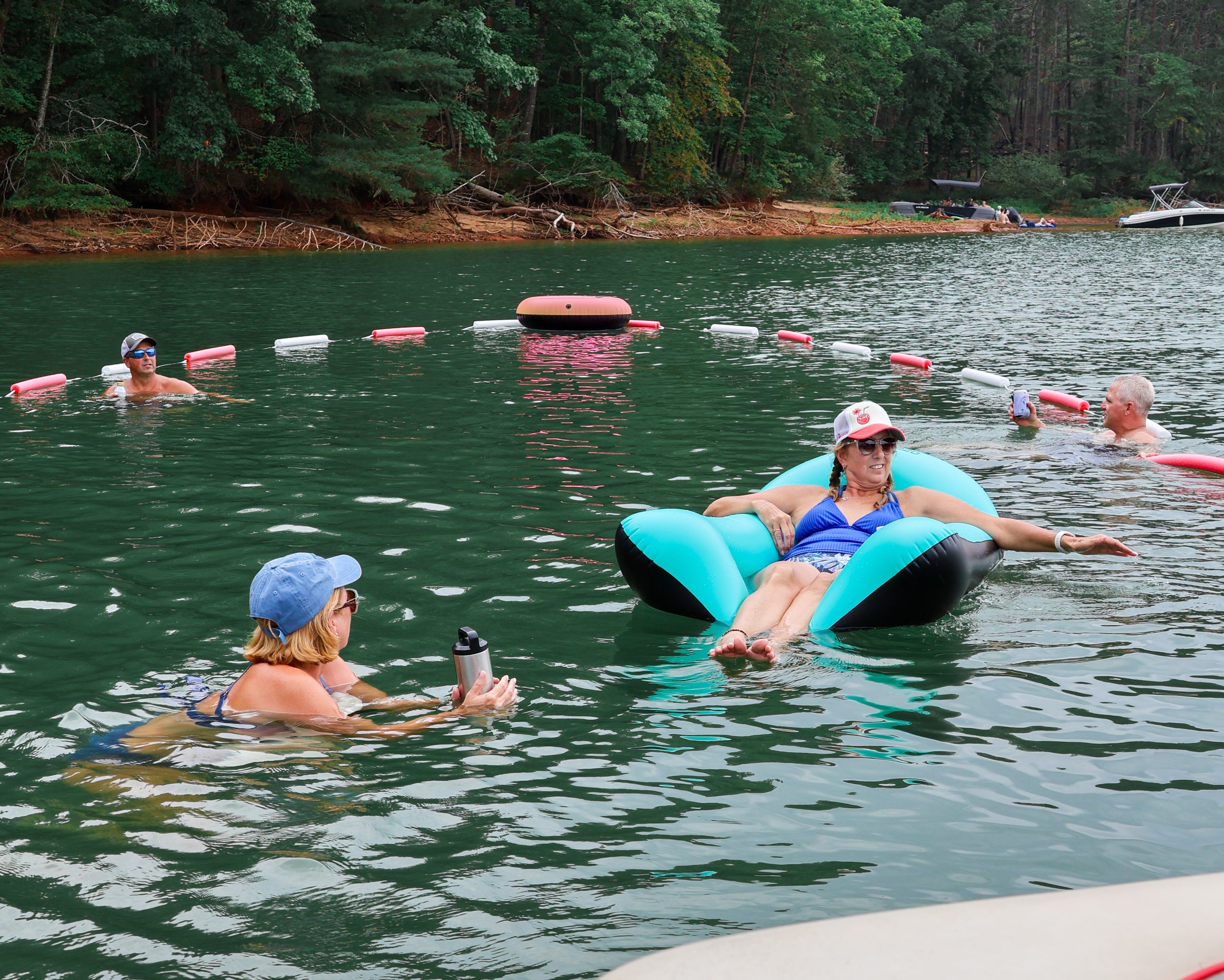 Friends enjoying a floating swim area with the Original Cove Corral™ at the lake, showing how to keep floats from drifting away while relaxing in the water.